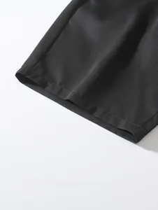 Close-up detail of the hem and woven fabric texture on black men's beach shorts