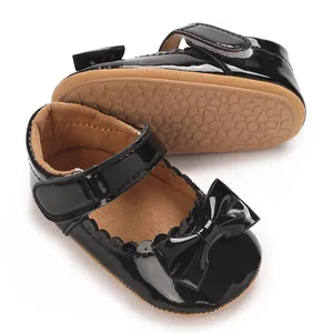 Detalle de los zapatos de charol negro para bebé con lazo y suela de goma con agarre