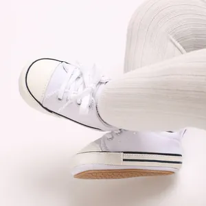 Close-up shot of white soft-soled baby canvas pre-walker shoes with ribbed tights