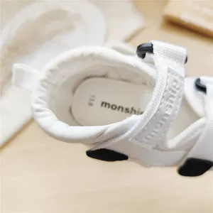 Detailed view of white Monship baby walking sandals featuring an adjustable velcro strap