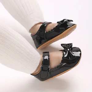 Primer plano de zapatos de charol negro para bebé niña con lazo y cierre de velcro