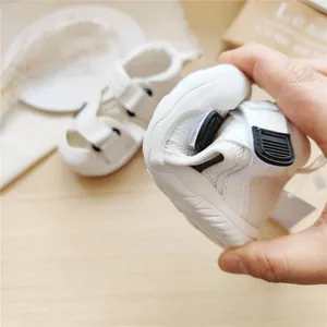 Flexible white toddler sandal being bent to show soft rubber sole detail