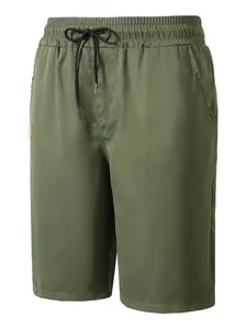 Close-up of olive green woven men's beach shorts with elastic waist and black drawstring