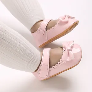Detalle de zapatos de charol rosa para bebé con lazo decorativo y borde festoneado
