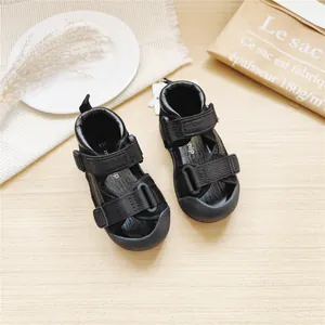 Close-up view of black monship baby walking sandals for toddlers on a wooden table