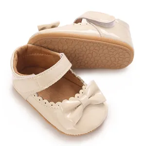Detalle de zapatos de princesa para bebé en charol beige con lazo y bordes ondulados