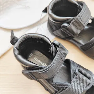 Detailed macro view of black monship baby walking sandals with mesh and velcro straps