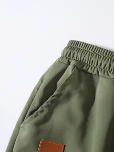 Detail of elastic waistband and pocket on men's olive green woven beach shorts