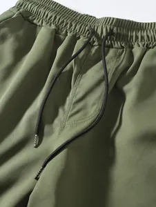 Macro detail of olive green men's woven shorts with elastic waist and drawstring.