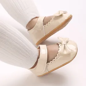 Primer plano de zapatos de princesa para bebé en charol crema con lazo y bordes festoneados