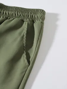 Close-up detail of olive green woven beach shorts with elastic waistband and side pocket