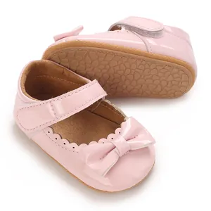 Primer plano detallado de zapatos de princesa para bebé en charol rosa con lazo decorativo.