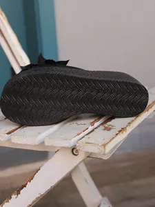 Detail of the non-slip wavy texture on the sole of black wedge platform sandals