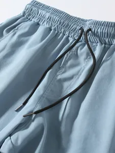 Detailed macro shot of light blue woven beach shorts with elastic waist and black drawstring