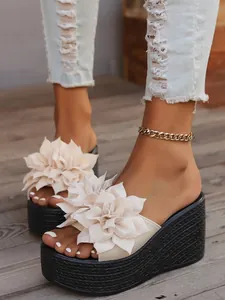 Close-up detail of beige platform wedge sandals with 3D fabric flower decor