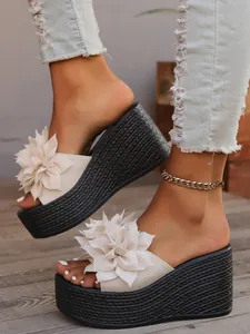 Detail of women's wedge platform sandals with large cream floral decorative accents