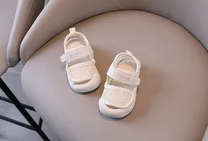Κοντινή λεπτομέρεια από λευκά βρεφικά πέδιλα με δίχτυ και μαλακή σόλα σε γκρι φόντο καρέκλας