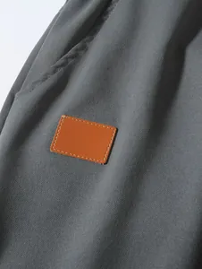 Close-up of gray woven fabric texture and brown leather patch on men's beach shorts