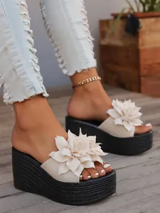 Detailed view of beige wedge sandals with elegant 3D flower decoration.