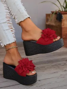 Side detail view of red flower platform wedge sandals featuring black woven thick soles
