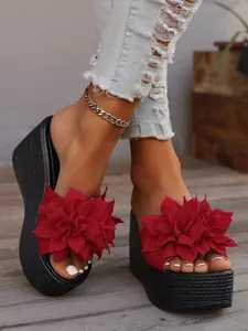 A close-up view of elegant red floral platform wedge sandals with textured black sole