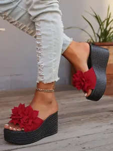 Stylish red floral platform wedge sandals with a black braided thick sole on wooden deck