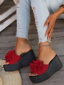 Close-up of stylish red flower wedge sandals with high black woven platform soles