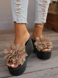 Close-up of elegant beige fabric flower decor on stylish black wedge platform slides