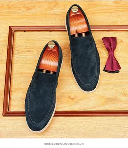 Top view of dark blue suede loafers with shoe trees and a bowtie