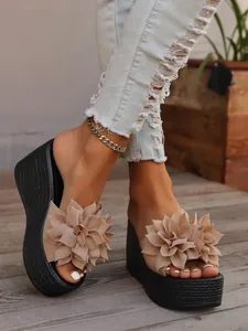 Detailed view of women's beige wedge sandals with large floral embellishment and black platform