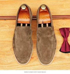 Top view of brown suede slip-on loafers on a wooden background with bow tie.