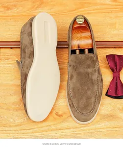 Detailed view of men's brown suede loafers with a soft cream sole on a wooden surface.