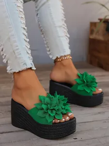 Detailed view of green platform slippers featuring a large floral design on wedge heels