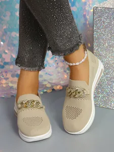 Detailed view of beige knitted loafers featuring a chunky gold chain ornament.