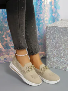 Detail view of breathable fly-knit casual shoes with gold chain and white wedge sole