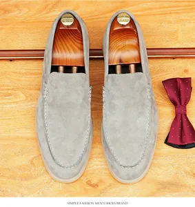 High-angle detailed view of grey suede men's loafers with wooden shoe trees and bow tie