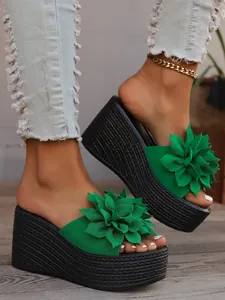 Detailed view of green platform wedge sandals with a large textured floral accent