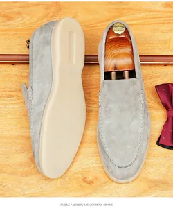 Macro view of grey suede men's loafers showing intricate stitch detail and soft sole texture