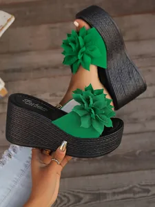 Close-up detail of stylish green wedge platform sandals featuring a large fabric flower