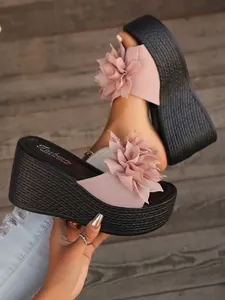 Detail showing the textured pink flower and woven platform sole of the wedge sandal.