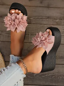 Detailed shot of stylish pink fabric flower embellishment on black wedge slippers