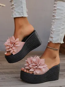 Detailed view of pink floral wedge platform sandals with textured black sole and denim.