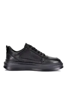 Vista lateral de zapatillas de cuero negro transpirable para hombre con suela gruesa.