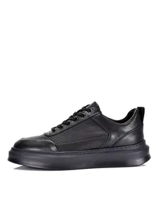 Zapatillas casuales de cuero negro para hombre con parte superior perforada y suela gruesa.