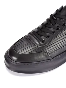 Detalle macro de zapatos informales para hombre en cuero negro con textura perforada