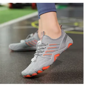 Close-up detail of grey and orange non-slip water shoes worn on a textured gym floor surface