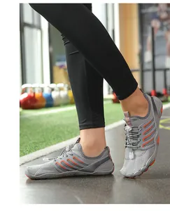 Detail view of grey mesh water shoes with orange stripes worn in a gym setting.