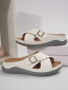 Seitenansicht weißer Keilsandalen mit Überkreuzriemen und goldener Zierschnalle