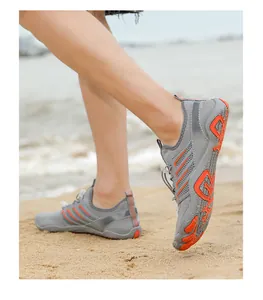 Close-up action shot of grey and orange non-slip water shoes worn on a sandy beach