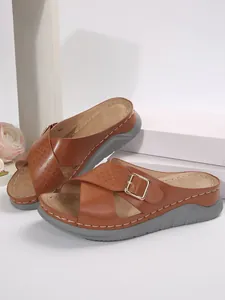 Detailansicht brauner Keilsandaletten mit Kreuzriemen und goldenen Schnallen